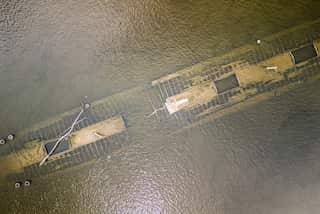 An aerial view shows the remains of a ship on a river