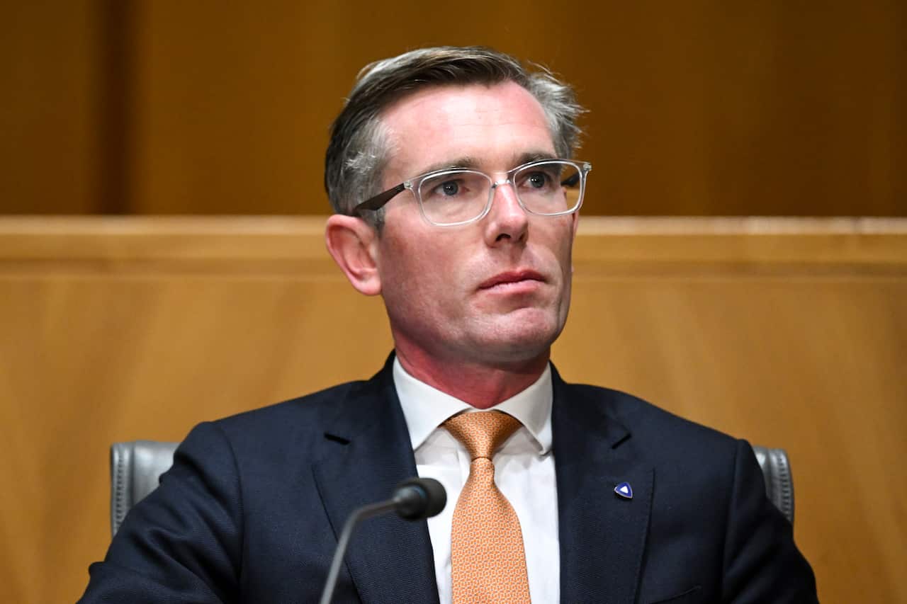 A man in a suit wearing glasses looks up seriously. 