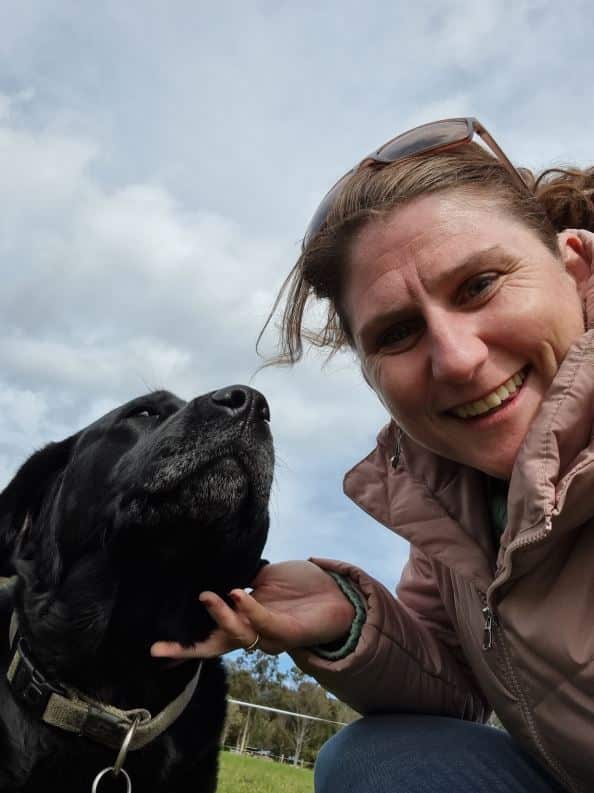 A woman stares into the camera with a black dog