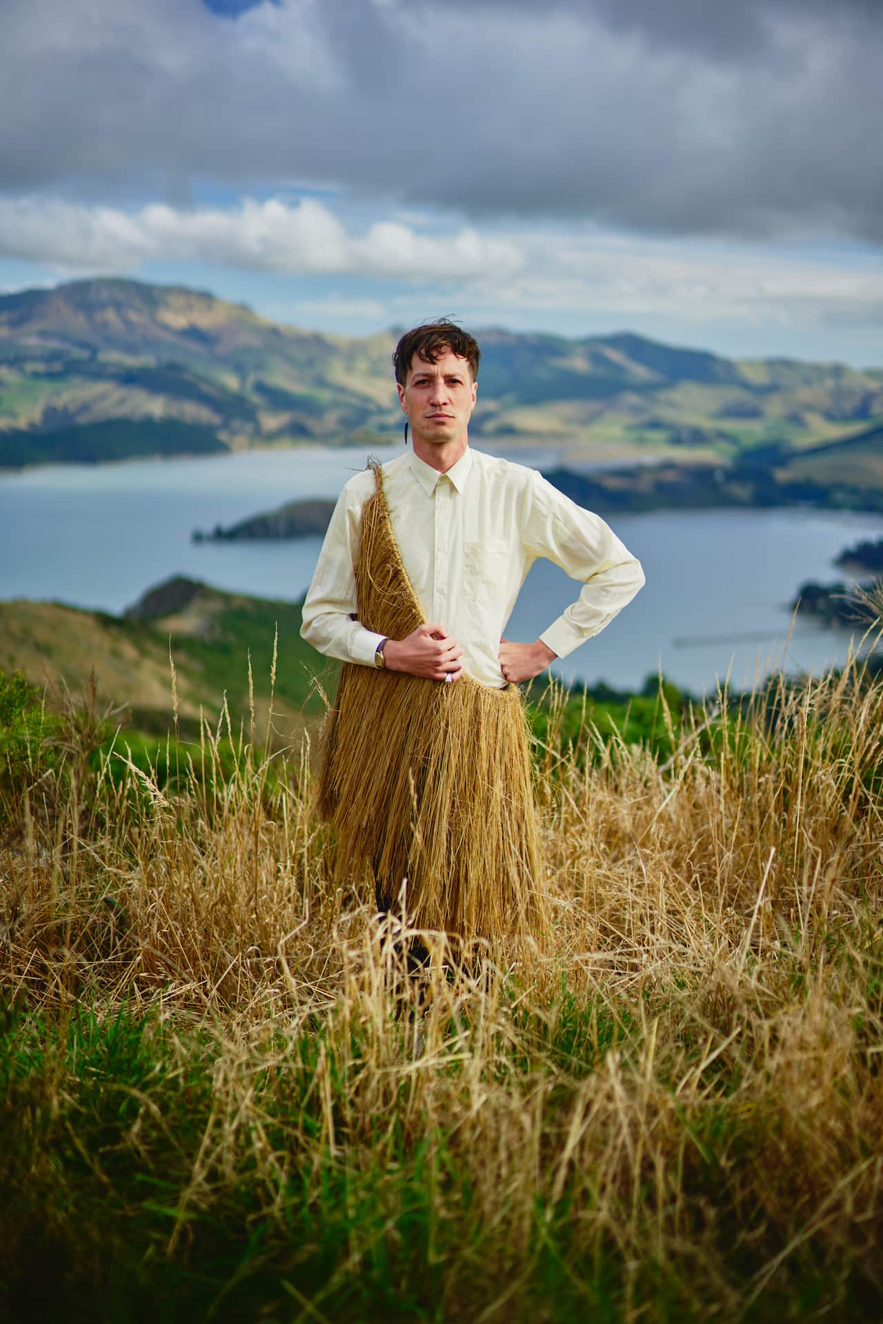 A man wearing a cream-coloured long-sleeve shirt and a rain cape made of light coloured dried leaves