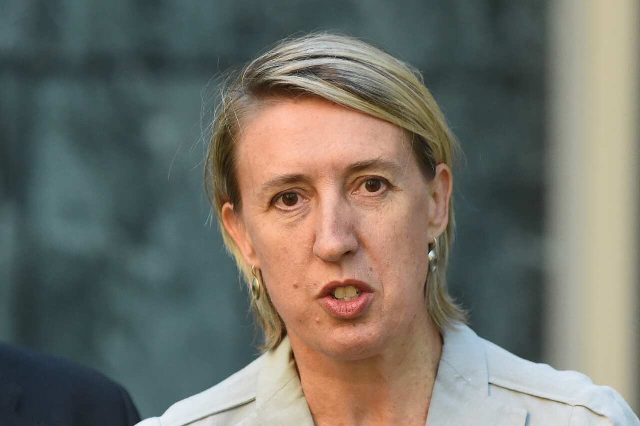 A woman with short blonde hair and earrings speaks.