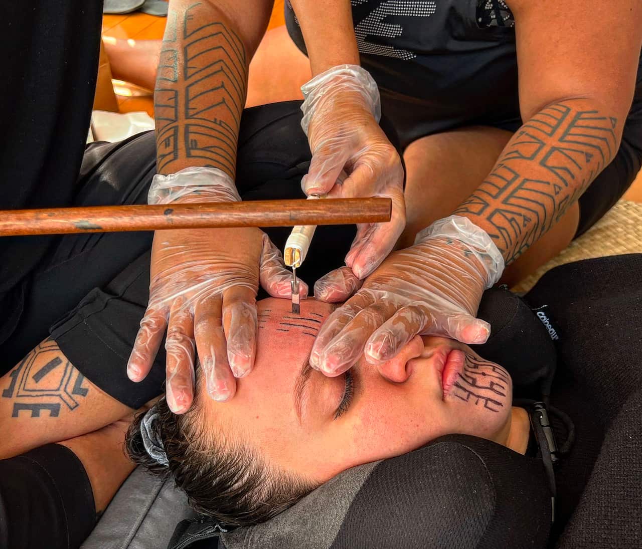 A woman's forehead is marked by another person wearing gloves