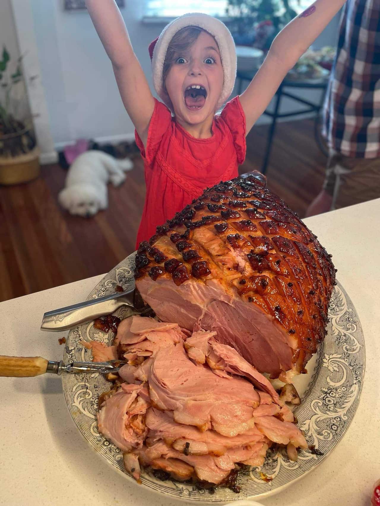 An excited young girl standing in front of a Christmas ham