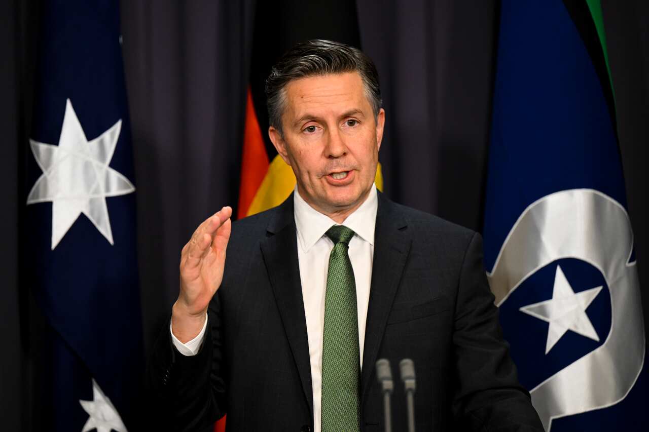 Health Minister Mark Butler speaks and gestures while standing at a lectern