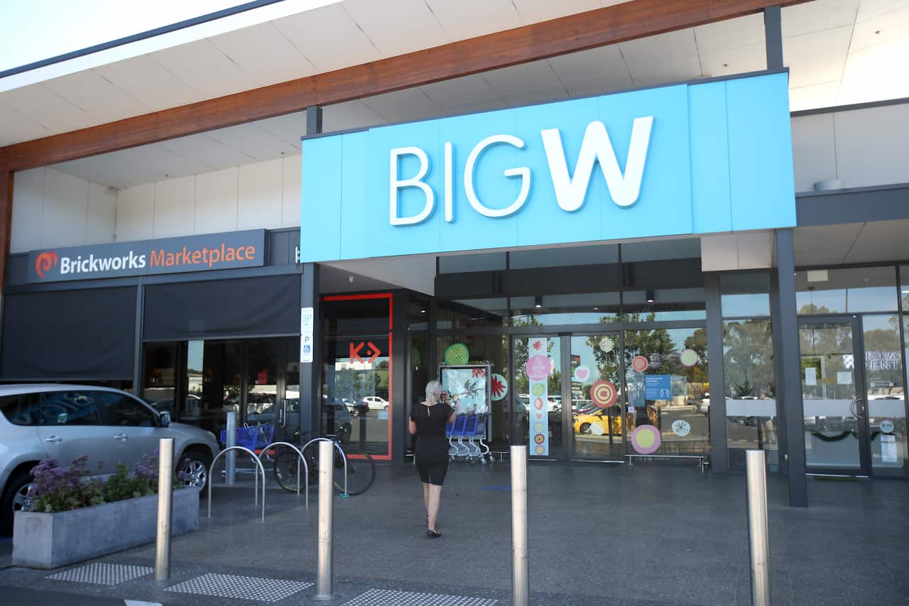 A person walking towards the entrance of a shopping centre. A sign above reads: "Big W".