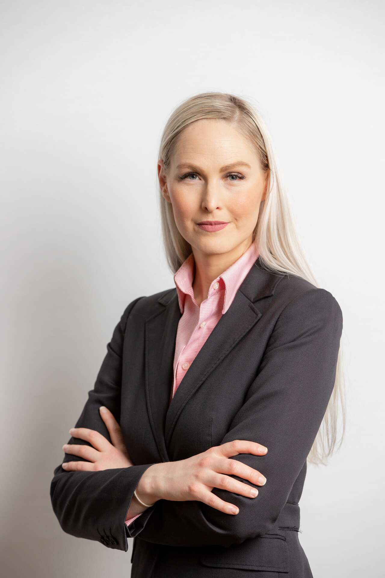 A woman in a suit standing with arms folded