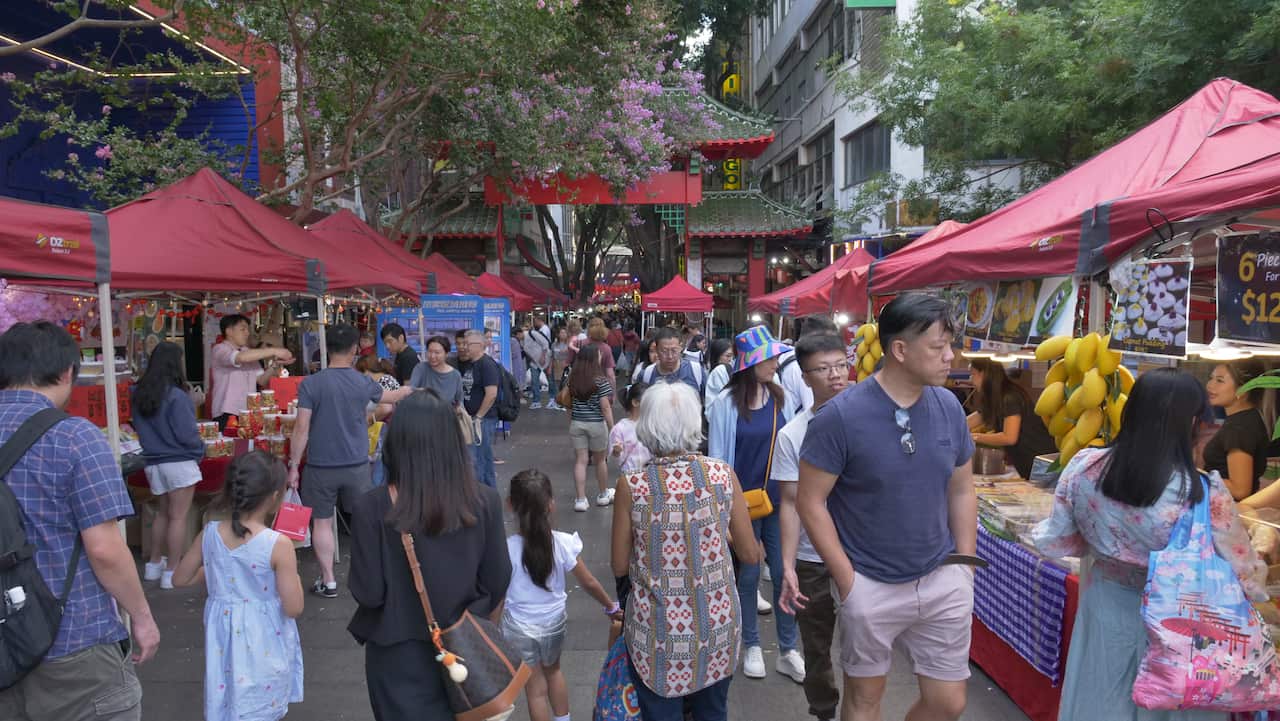 People walk past market stalls.