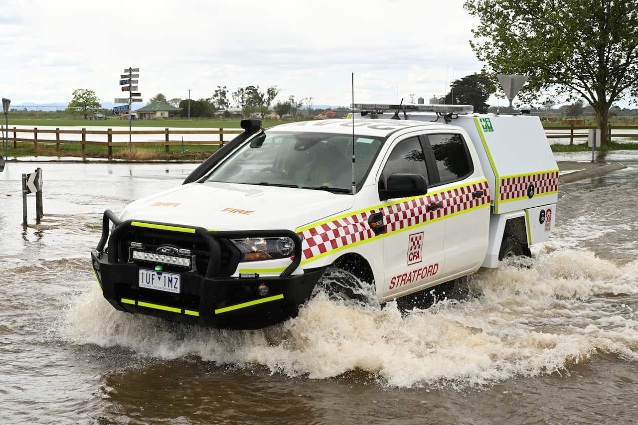 An emergency vehicle drives through floodwater.