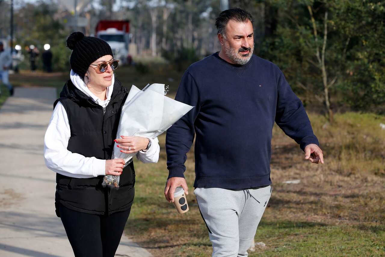 A couple walking with flowers in the site of the bus accident. 
