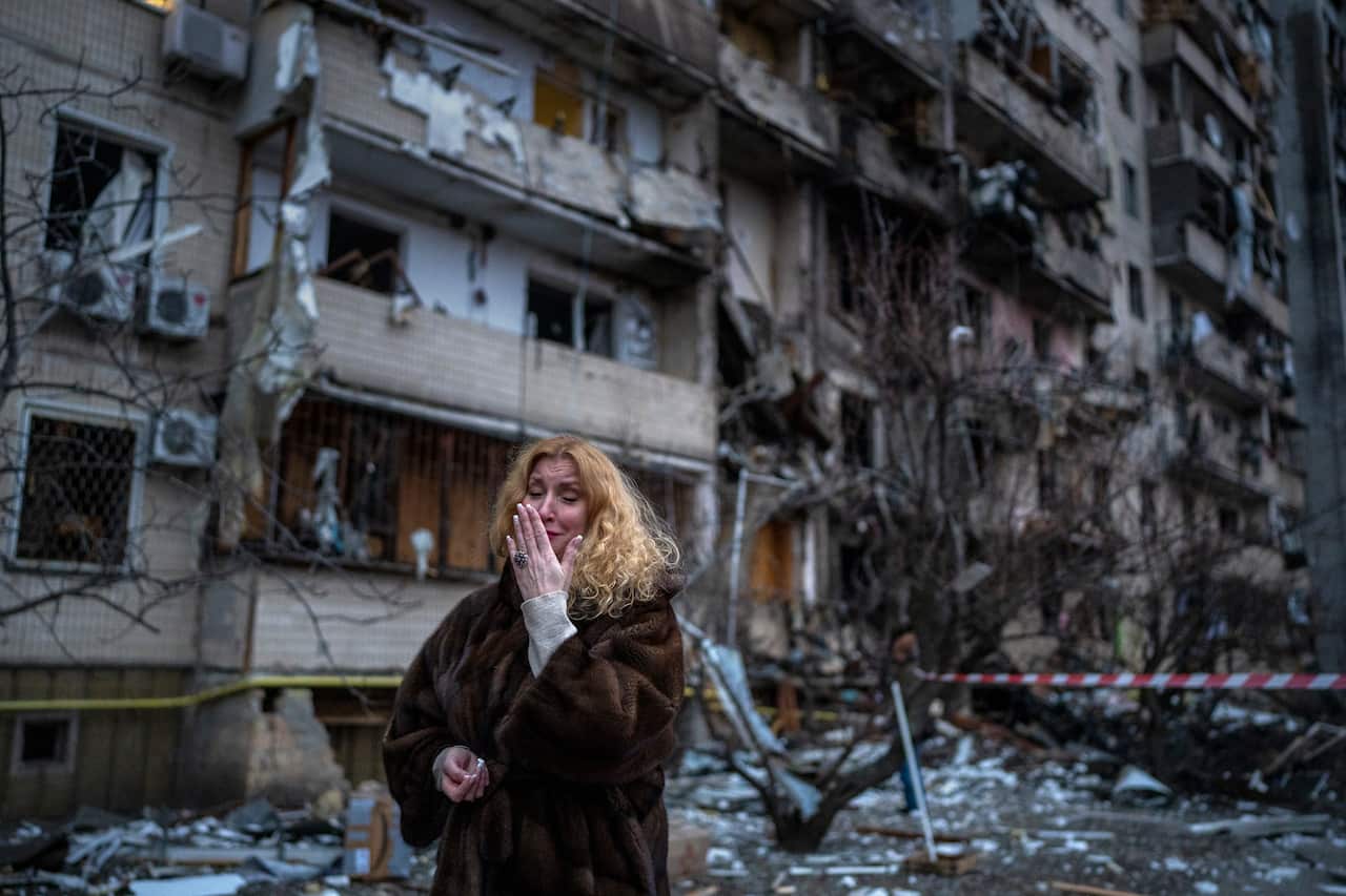 A woman reacts next to her house following a rocket attack in Kyiv, Friday February 25, 2022.