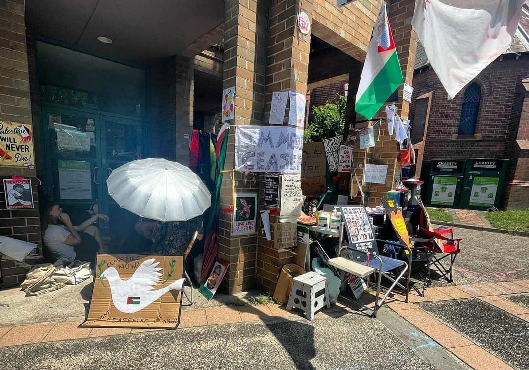 Tables and chairs in front of a brick building are crowded with messages of support for Palestinians and calls for a ceasefire