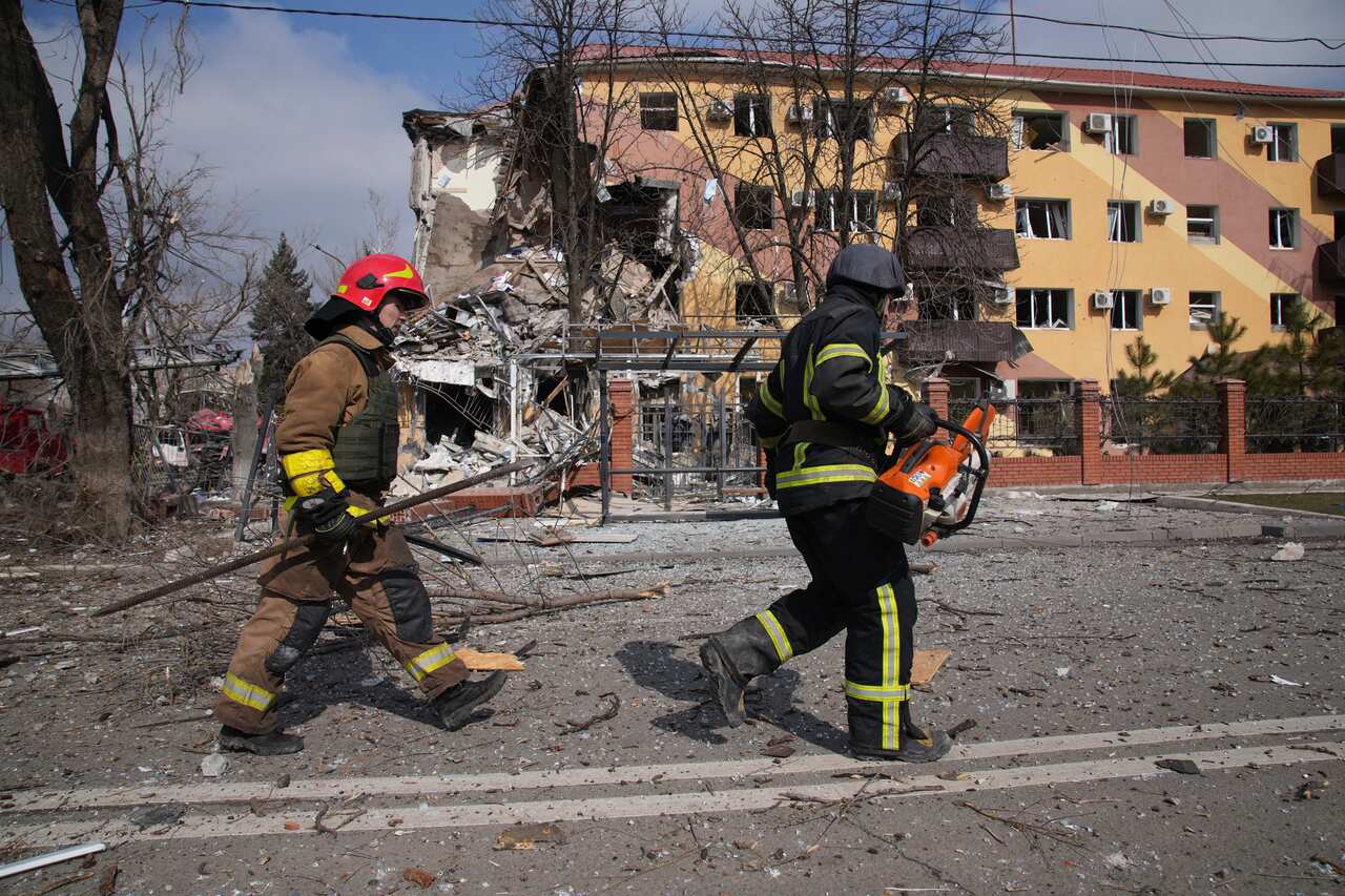 Firefighters walk past a damaged by shelling building in Mariupol, Ukraine.