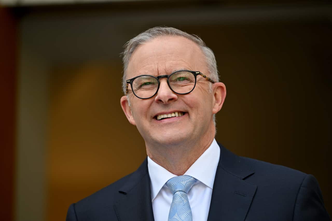 Man in suit and glasses smiling.
