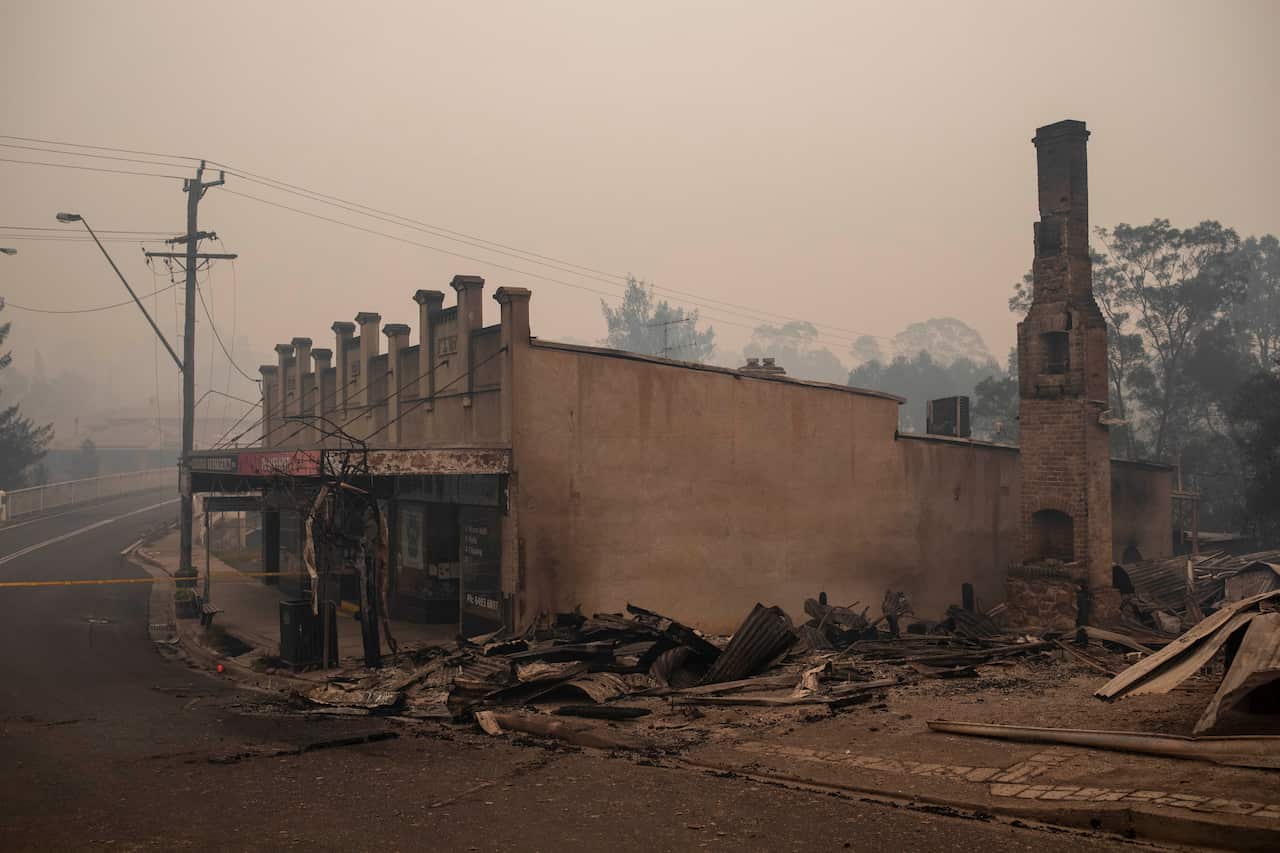 Ruins of a burnt building surrounded by grey smoke.