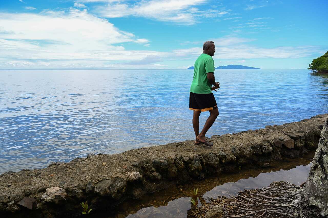 Tuiverata walks along a seawall in the village of Veivatuloa, 35kms west of Suva, Fiji on 13 December 2022. 