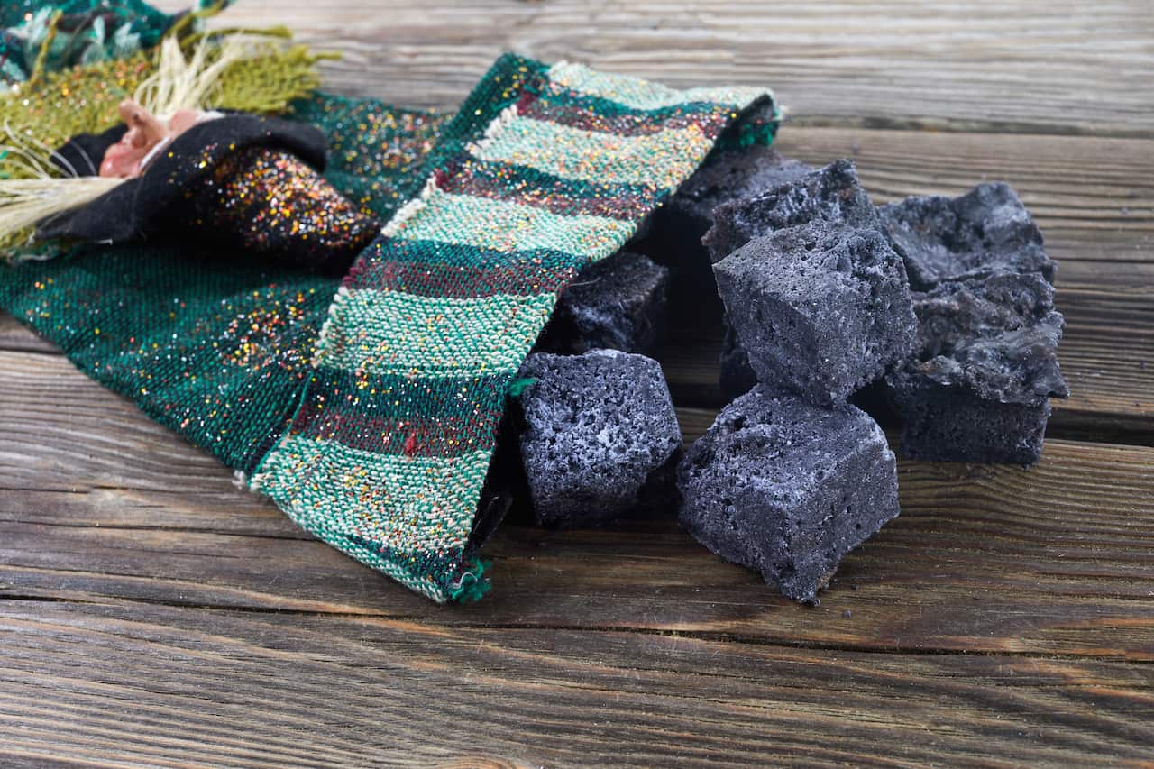 Befana sock with sweet coal and candy on wooden background. Italian Epiphany day tradition.