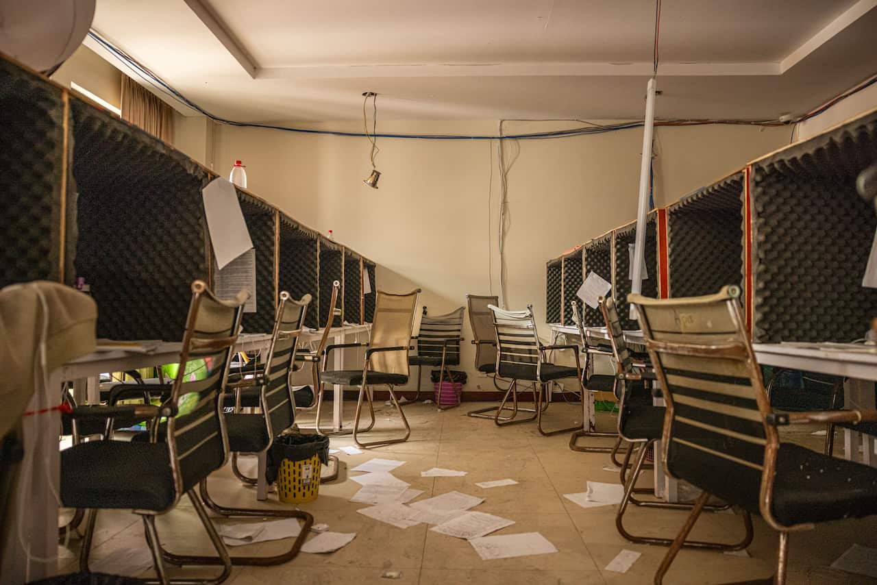 Tables and chairs and papers scattered on the floor under an outdoor tent