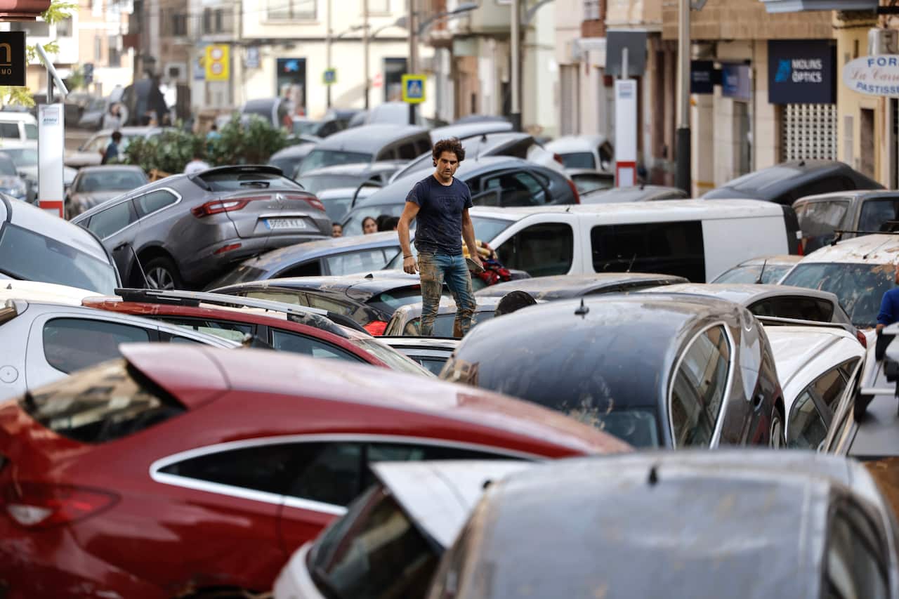 A man walks across a sea of wrecked cars