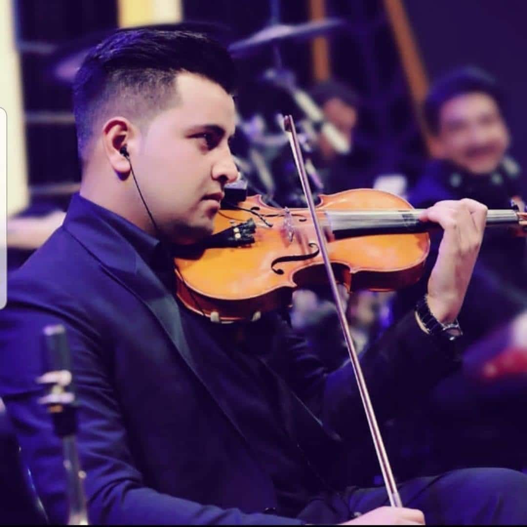 A man wearing a suit and an earpiece plays the violin.