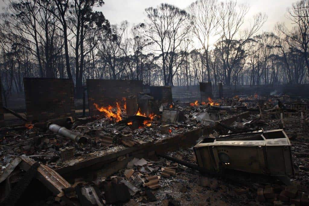 A burnt down house with flames.