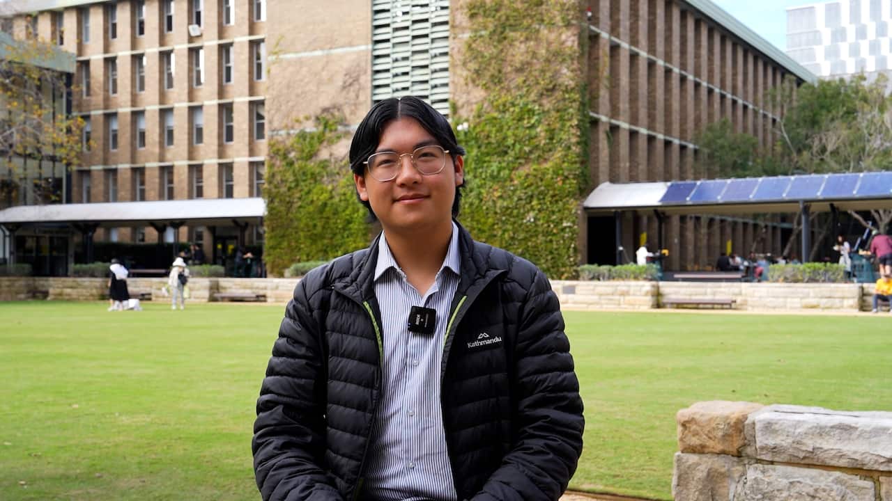 Anthony Ma, vice president of the UNSW Liberal Club sits in front of a UNSW lawn, grinning to camera.