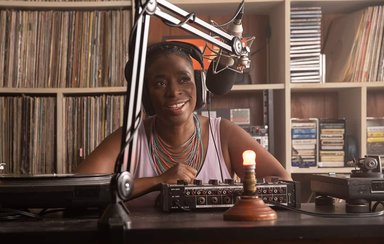 A woman in headphones sits in a low-tech radio studio.