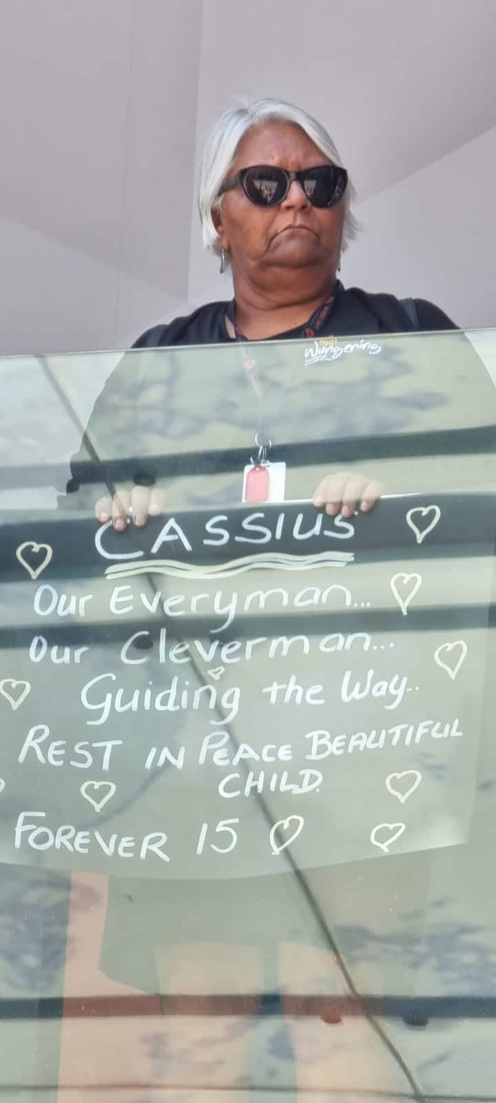 A woman holds a sign made for Cassius Turvey