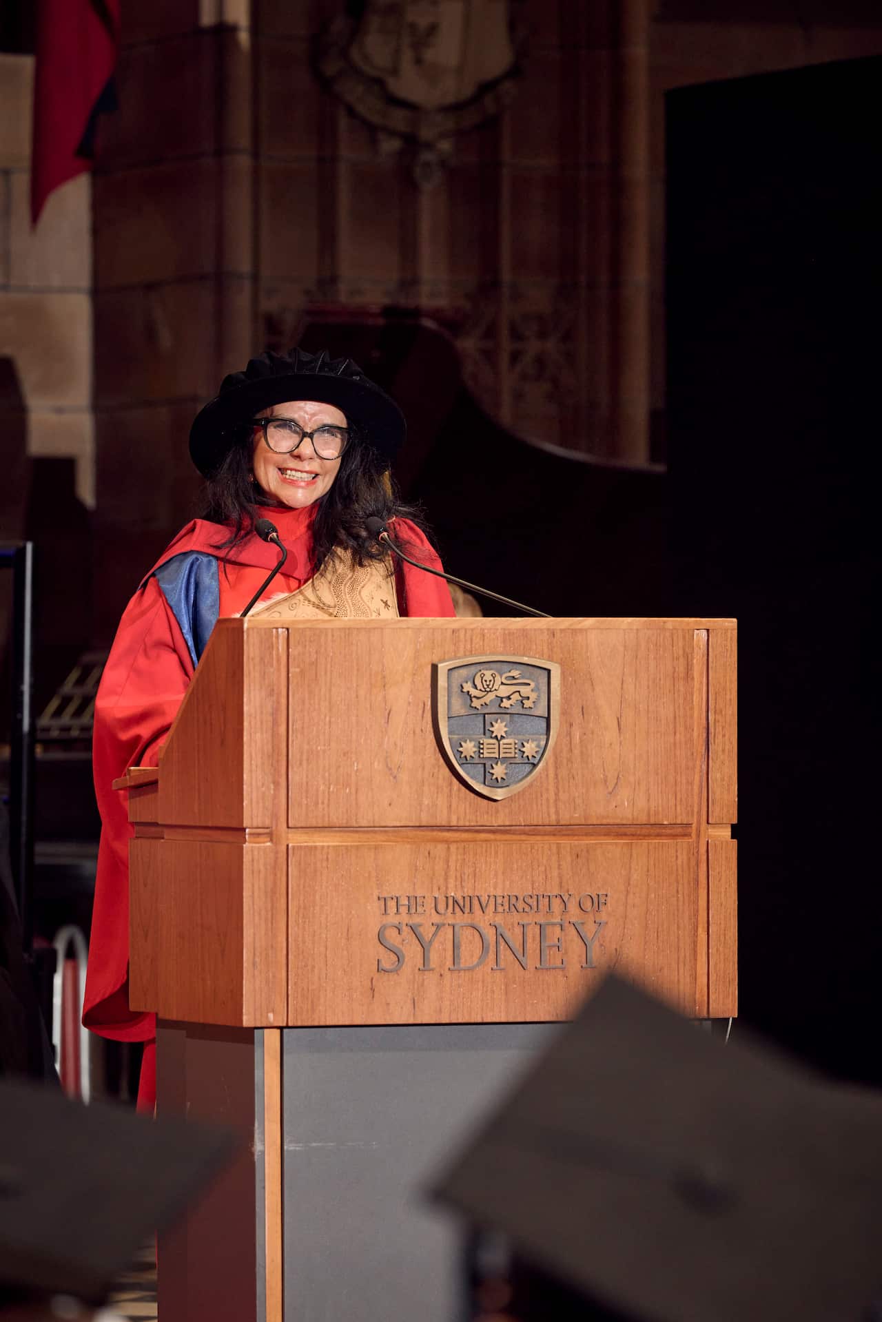 Linda Burney stands at a podium on stage to deliver a talk.