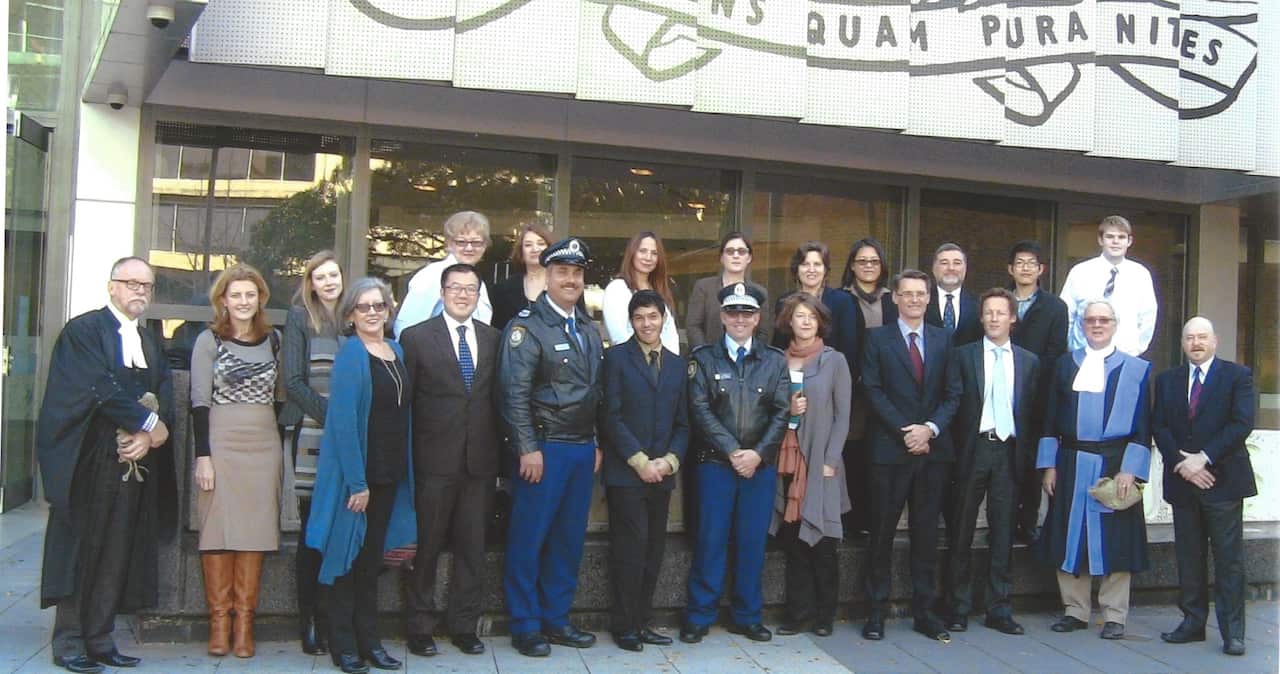 Participants in the 2014 mock trial in Sydney are shown standing together in a group photo outside the court in Parramatta. 