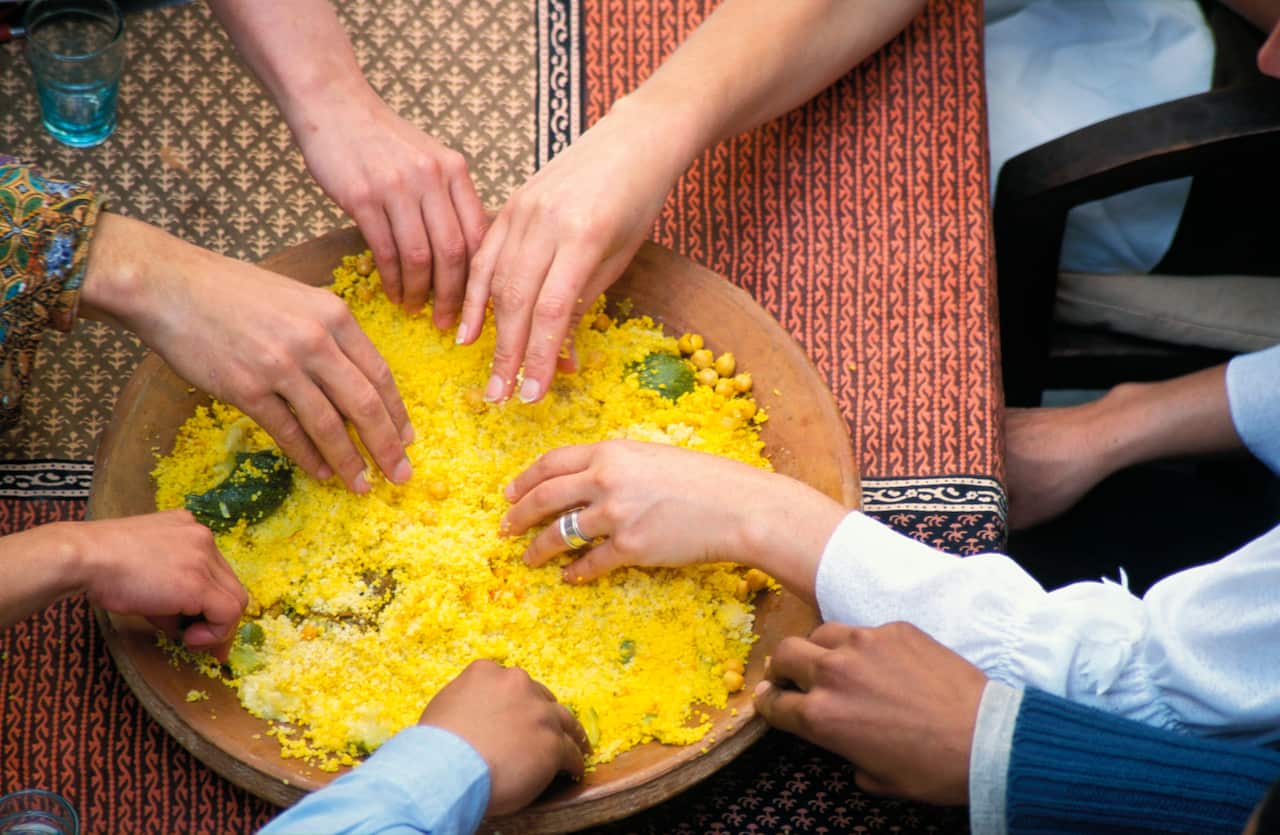 Hands in a bowl of couscous.