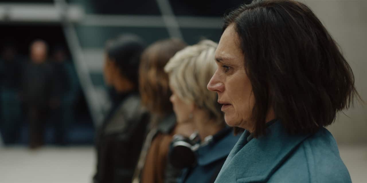 4 women stand in a line, the closest to camera is in focus looking nervous