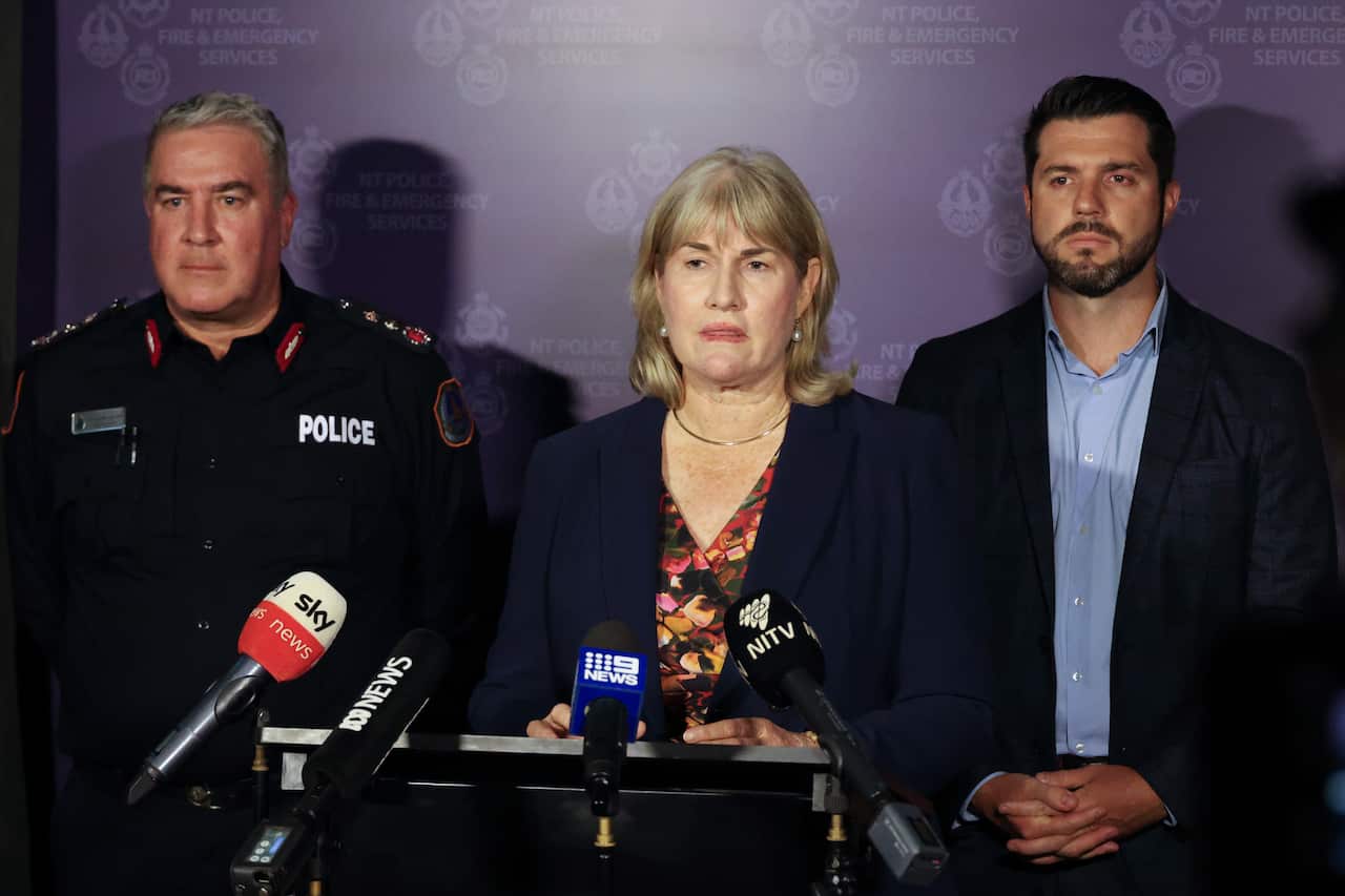 Three people speak to the media. 