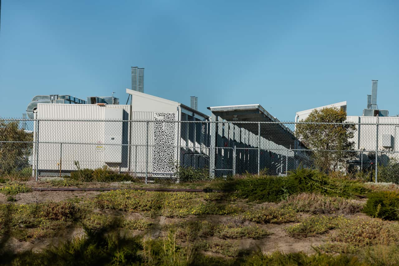 A row of one story buildings with awnings can be seen behind a chain link fence.