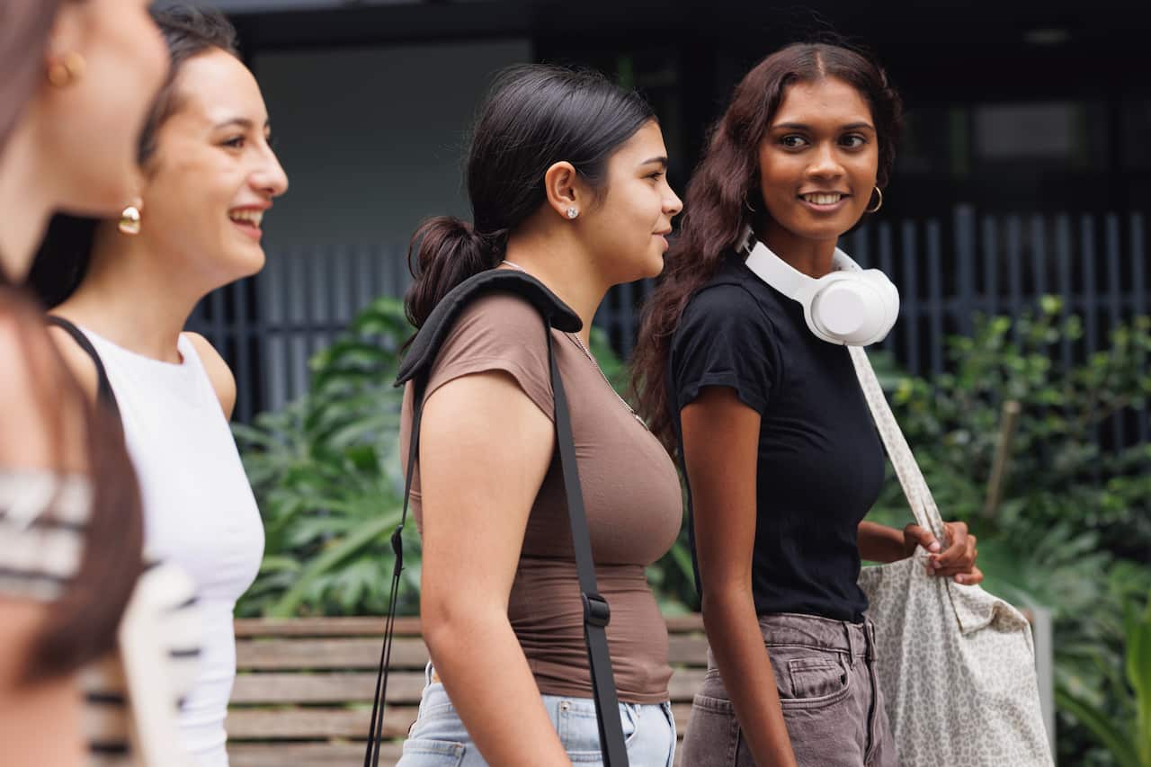 Diverse group of four university students walking through campus grounds