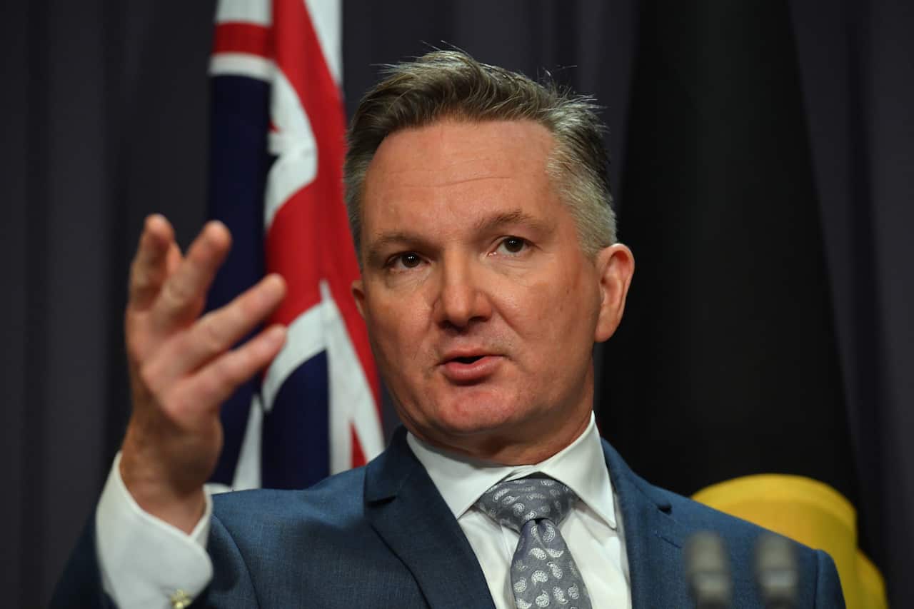 A man in a suit gesturing towards the camera