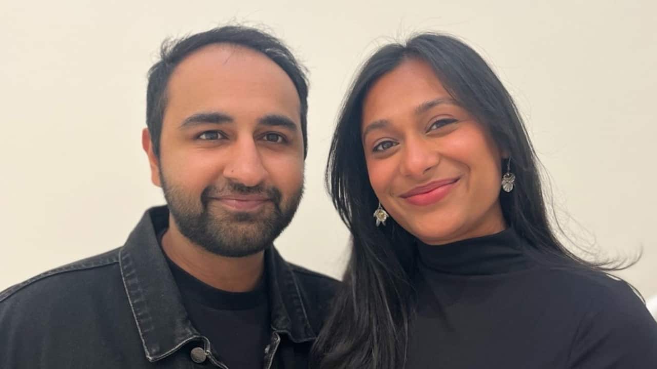 a closeup of a young man and woman both wearing black and smiling