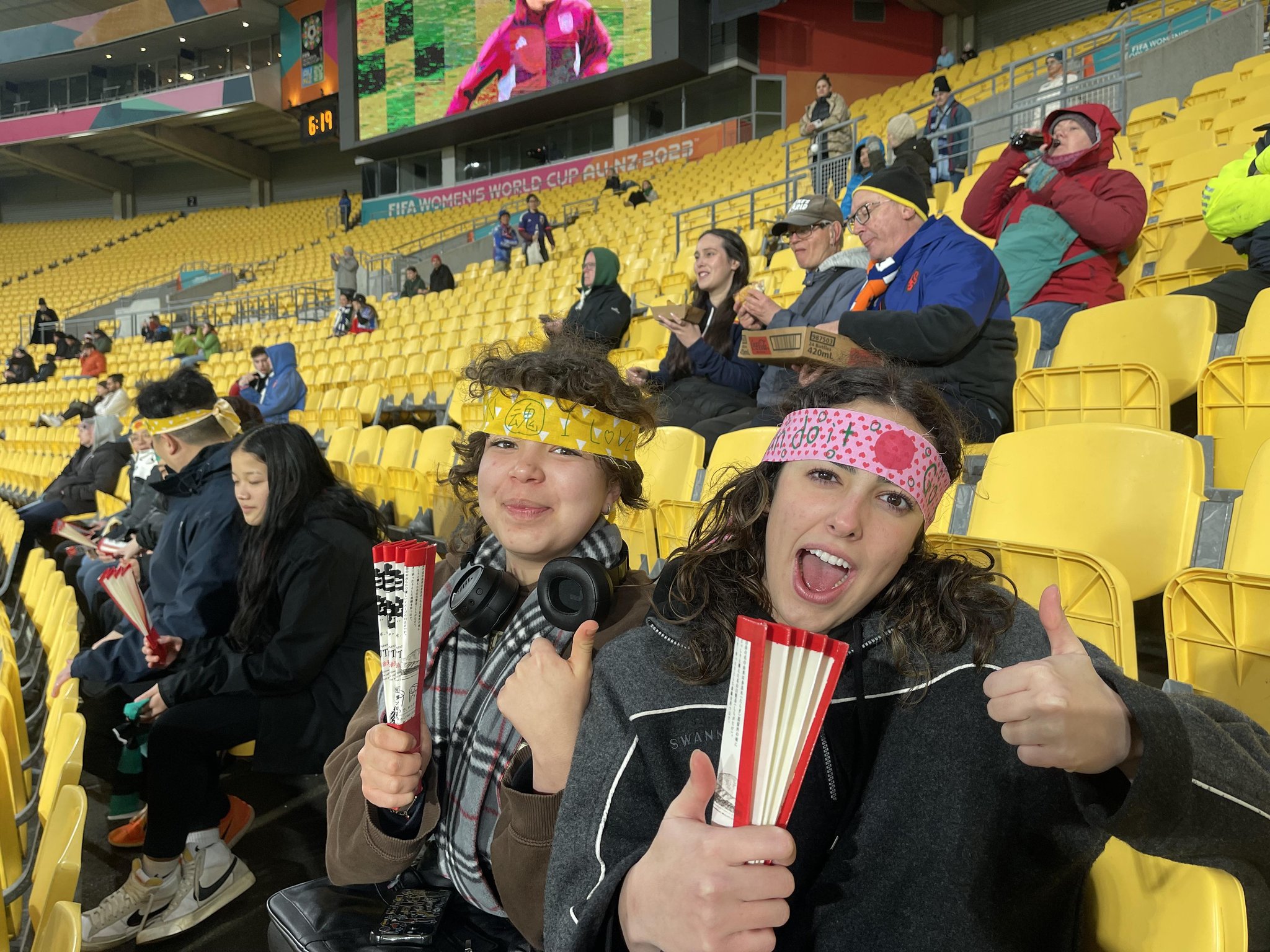 Football fans wearing a headband and holding a paper fan.