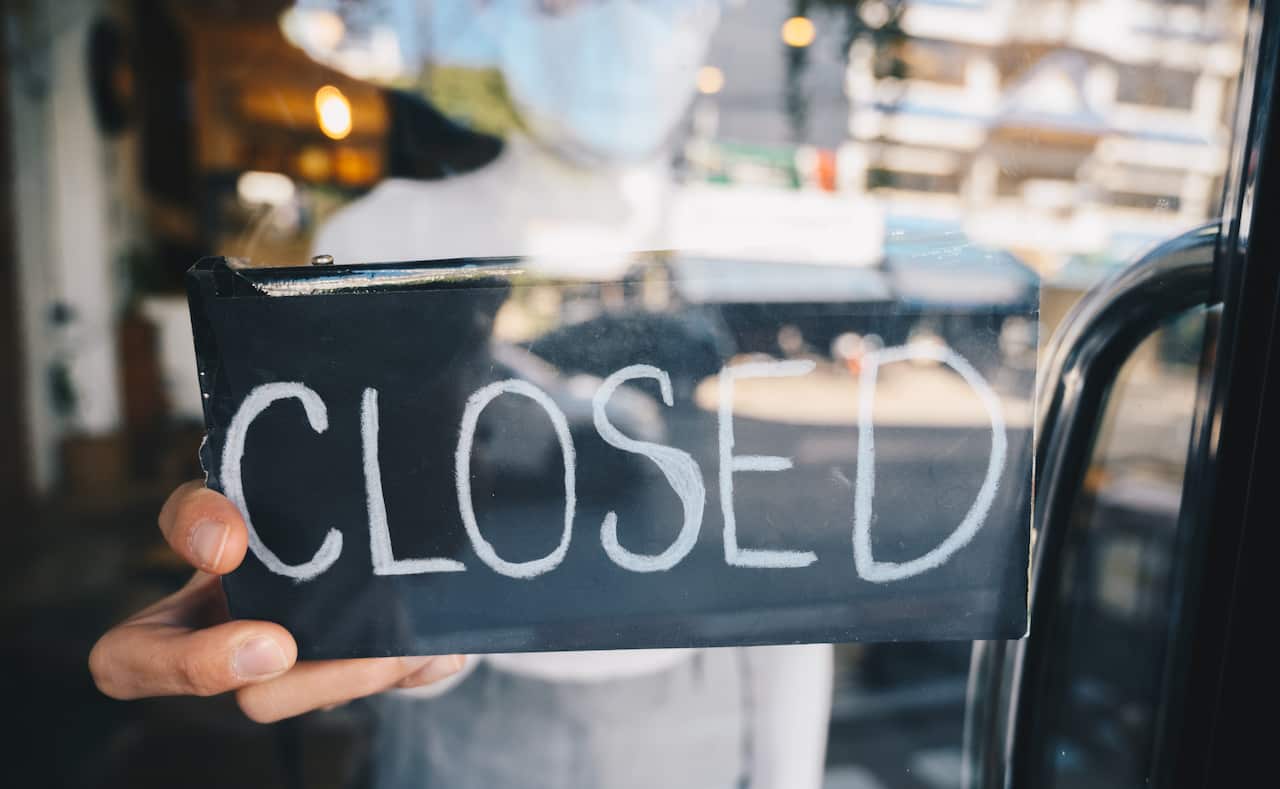 Cropped shot of business owner holding banner with closed word on door due to the novel coronavirus outbreak.