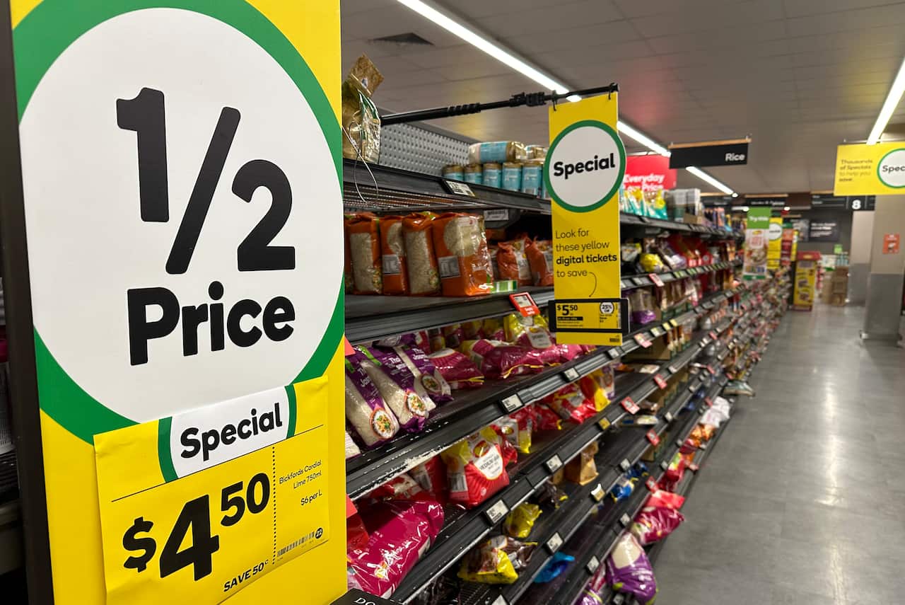 A supermarket aisle with 1/2 price and specials posters on it