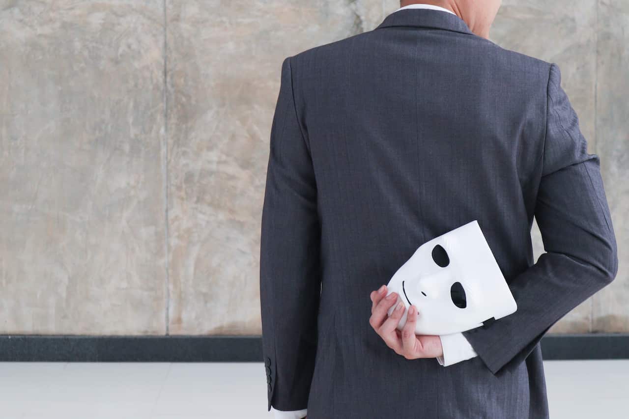 Businessman holding white mask in his hand dishonest cheating agreement.Faking and betray business partnership concept