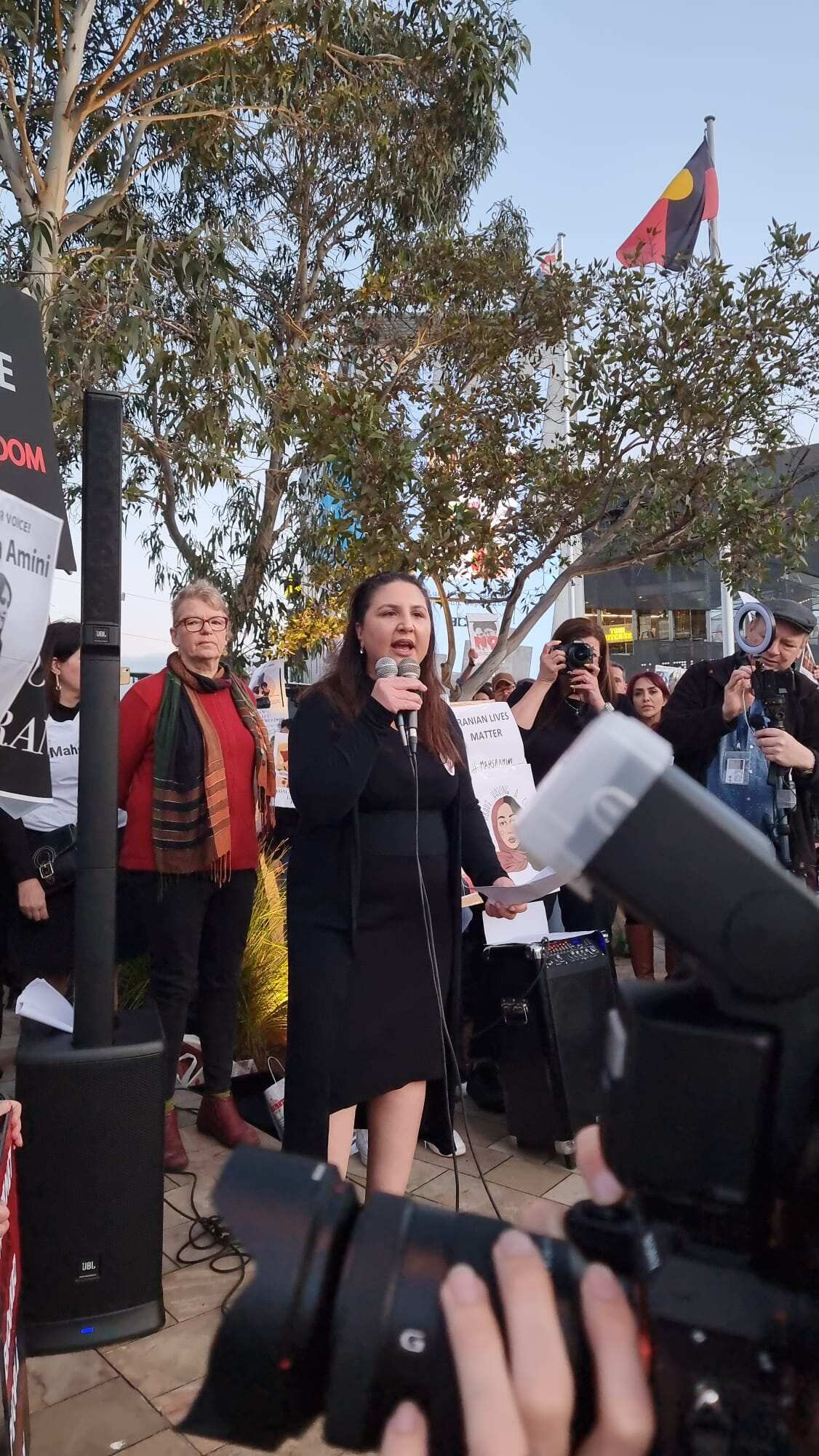 A woman talks into two microphones she is holding at a protest rally