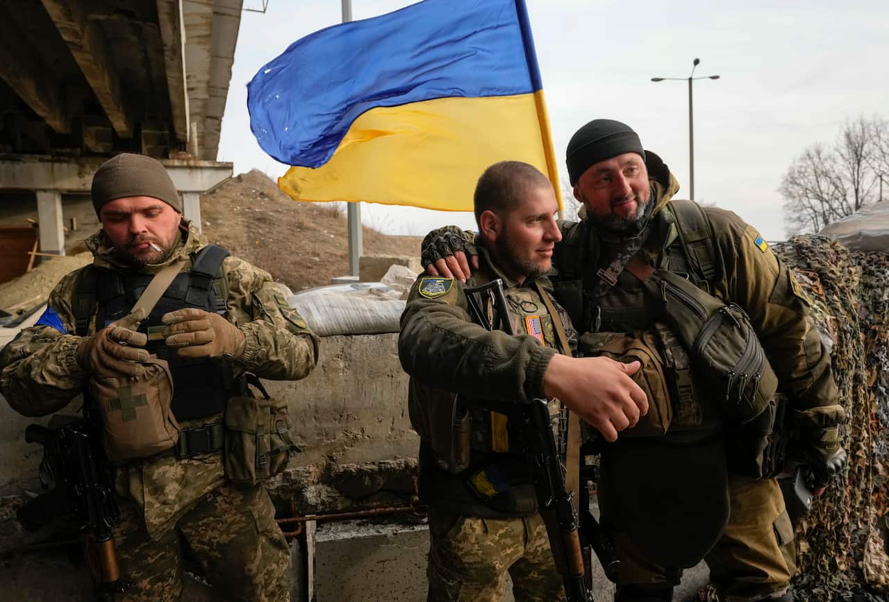 Three Ukrainian soldiers are seen talking.