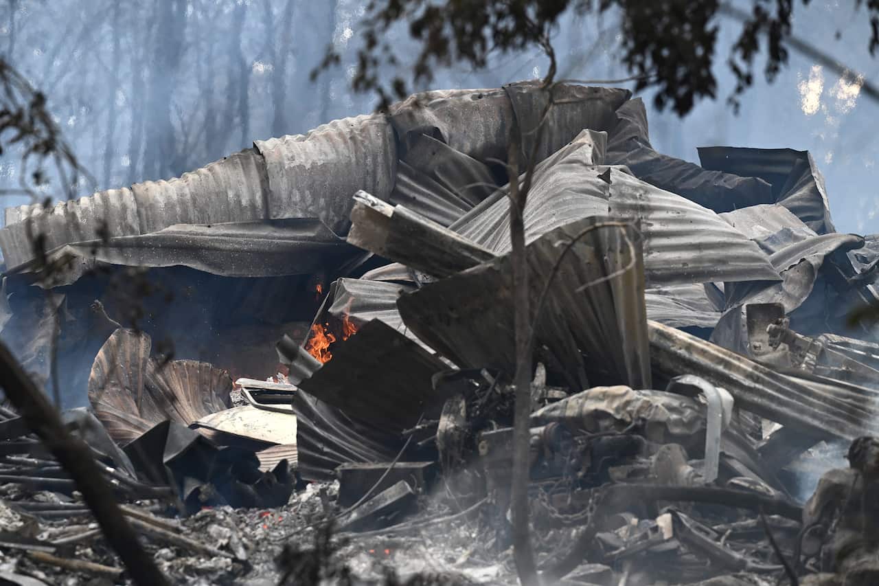 The rubble and wreckage of a destroyed home, with some flames still visible