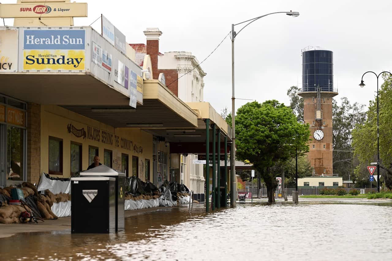 Sandbags against a building on a street that is flooded.