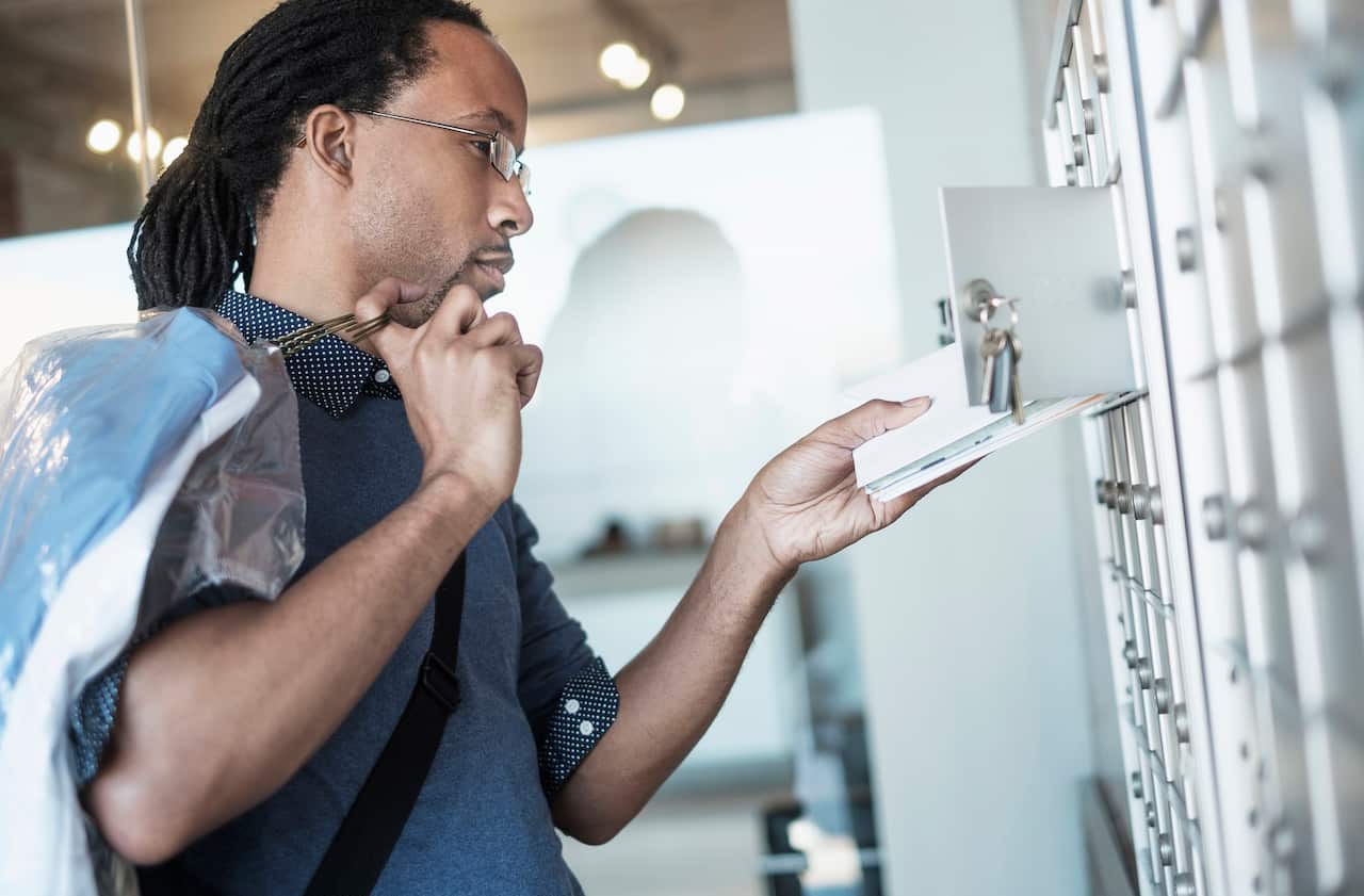 Black man gathering mail from post office box