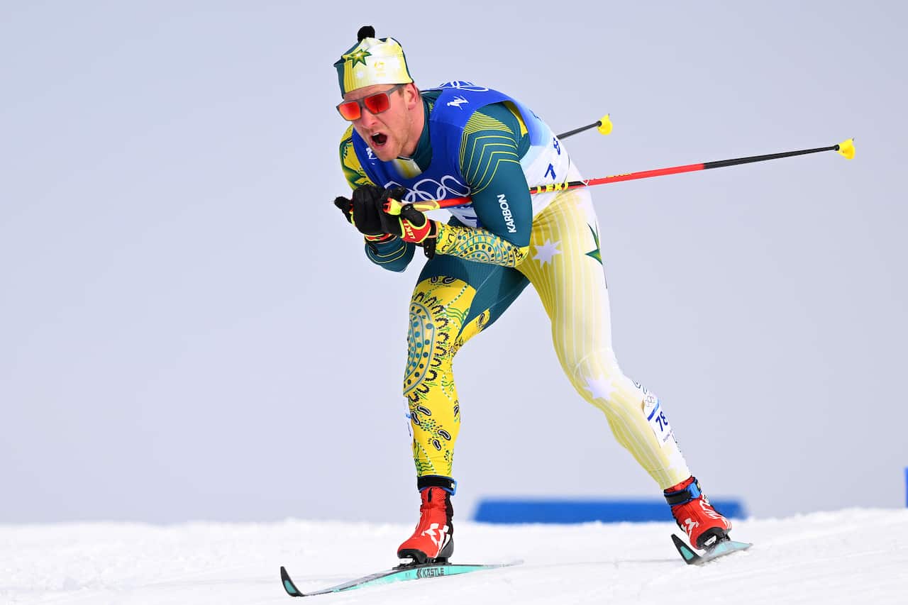 A man wearing a ski suit is skiing down a slope with poles by his sides