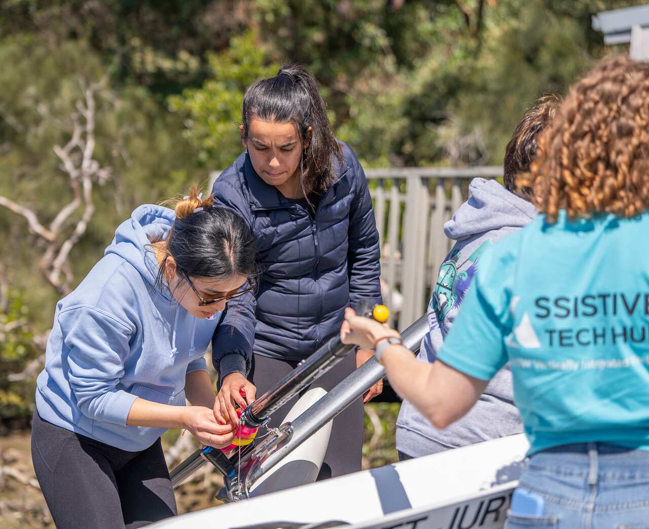 Two women working on metal device attaching an oar to a rowing boat