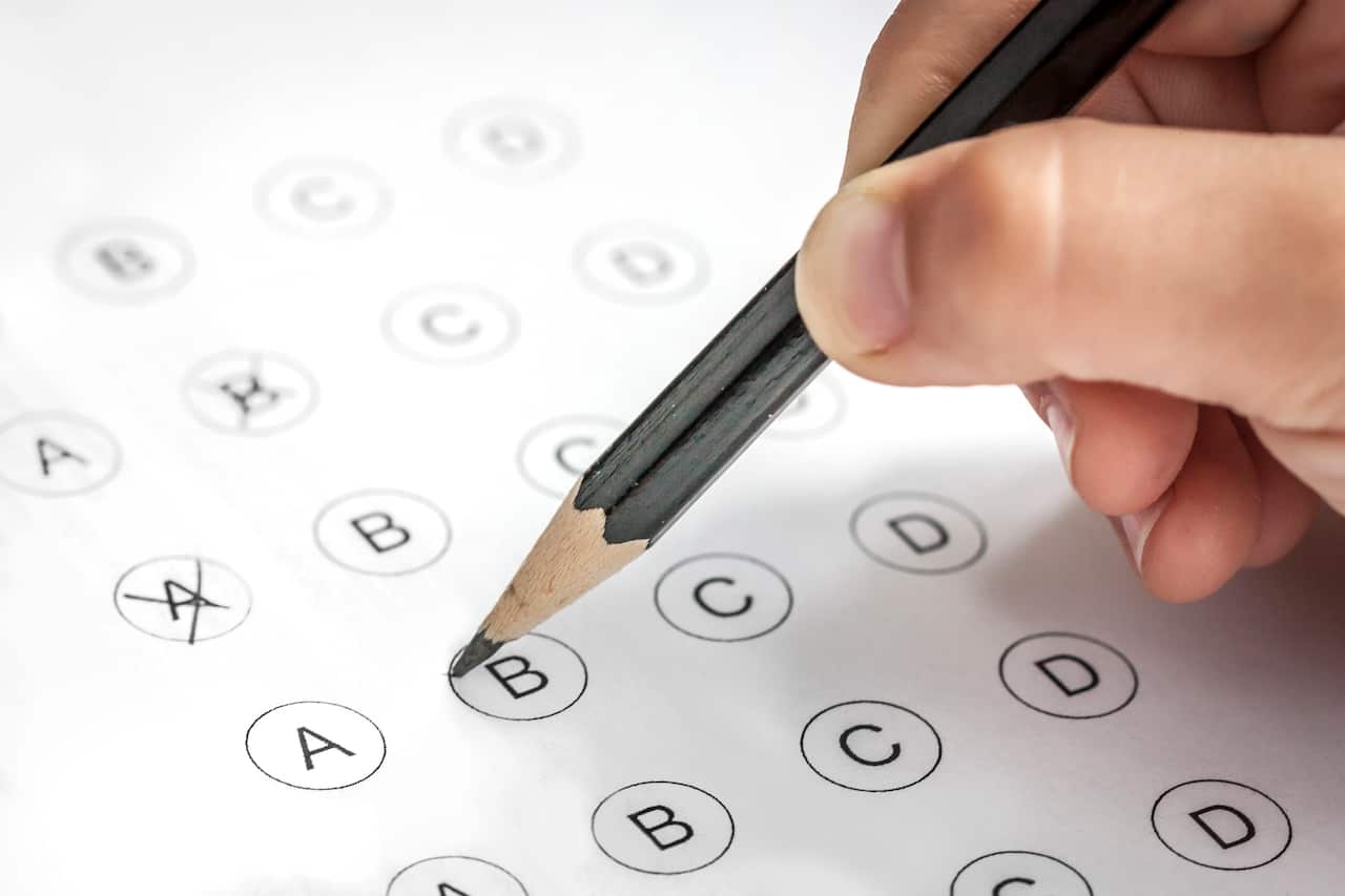 Child's hand filling in a multi-answer test with a pencil