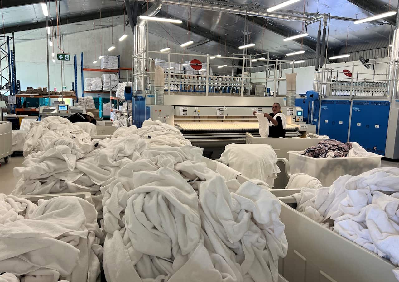 White washing including sheets and towels piled in a commercial laundry.