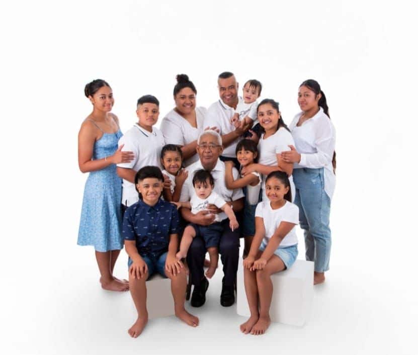 A portrait pic of a large family of mum, dad, a grandfather and 10 children. They are all wearing football strips.